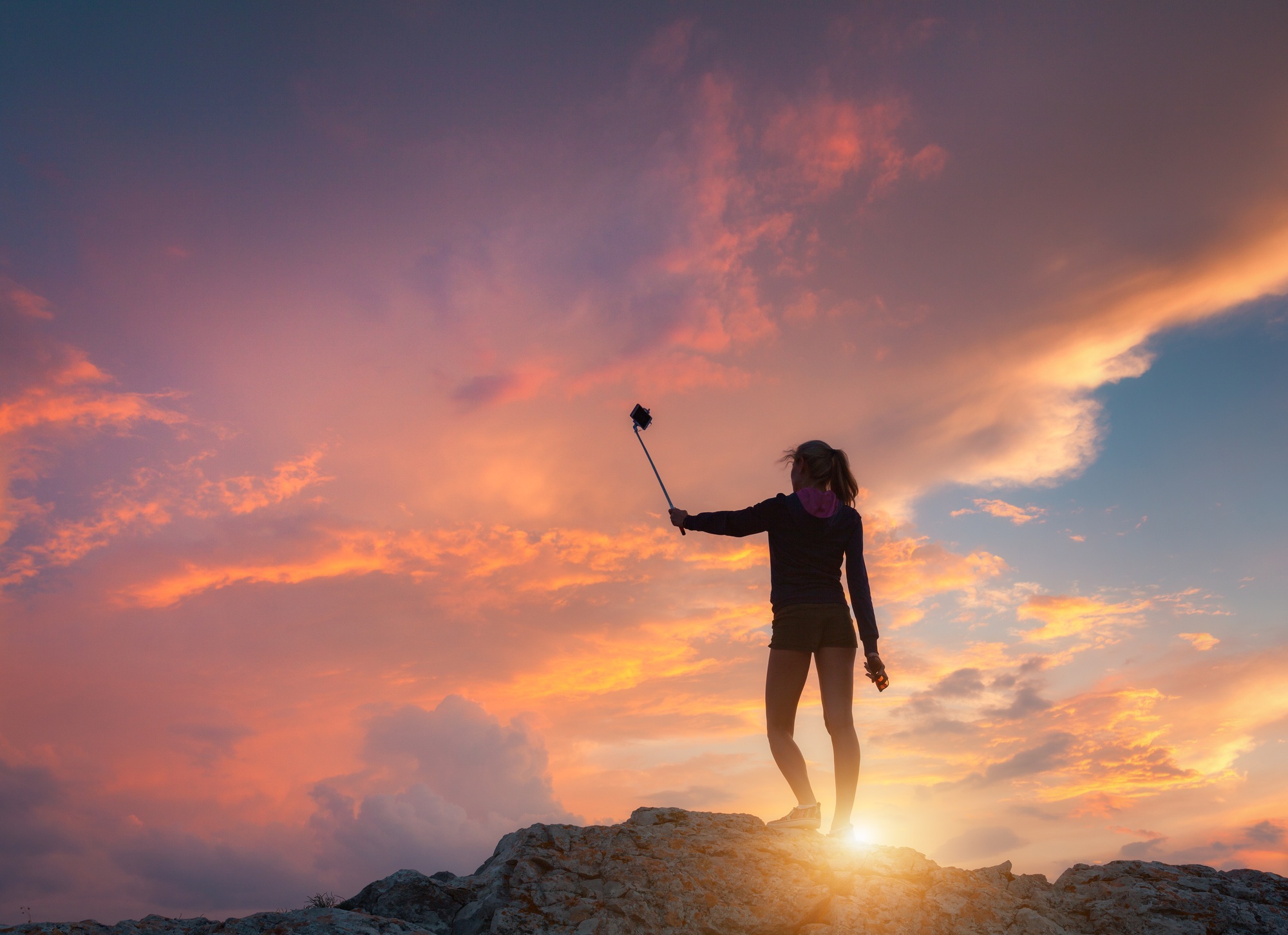 Beautiful young woman makes selfie for Instagram at sunset