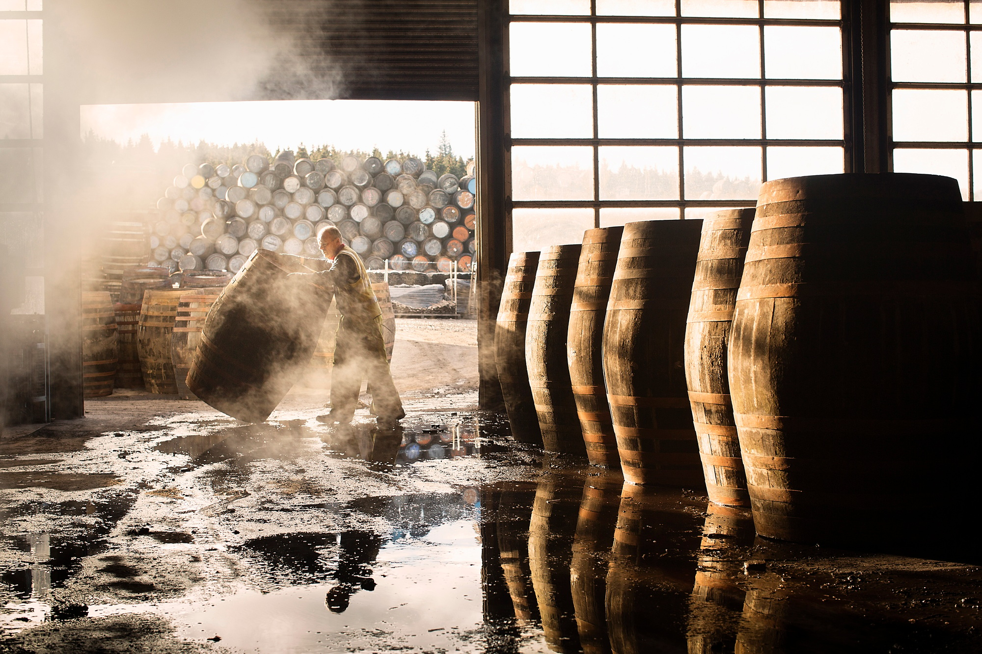 Male cooper working in cooperage with whisky casks